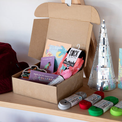 Roller skate gift box and accessories sit in on a wooden shelf with a disco tile tree