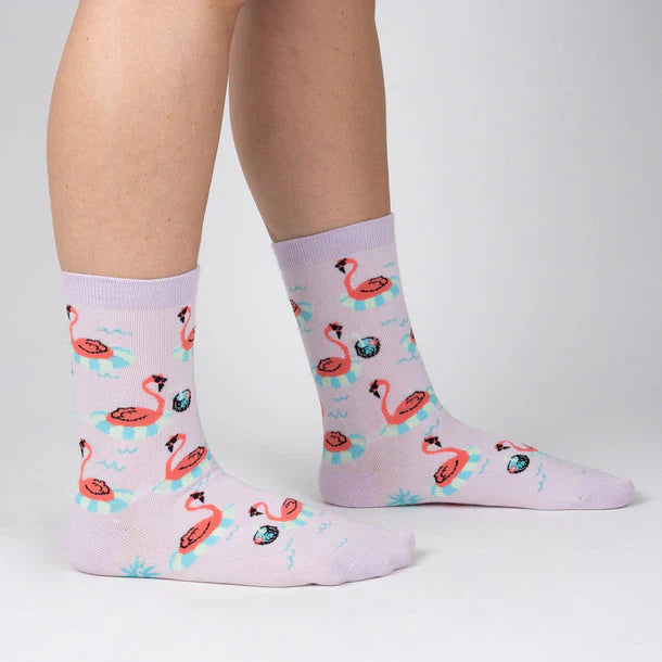 Pastel purple socks with flamingos wearing sunglasses floating around in pool rings.