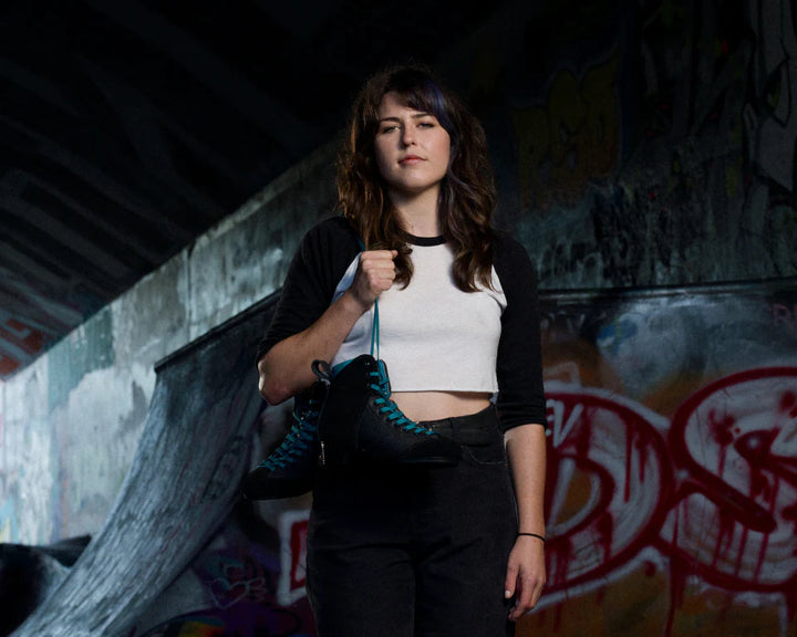 Lanna Thornhill at Canadian DIY skate park with her black Chuffed Skates pro boots slung over her shoulder.