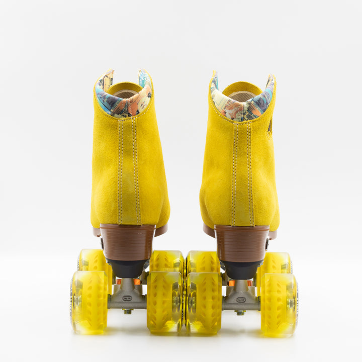 Moxi Roller Skates Lolly roller skates in Pineapple yellow with oyster laces and eyelets, tan sole, black plate and toe stop, matching yellow wheels.