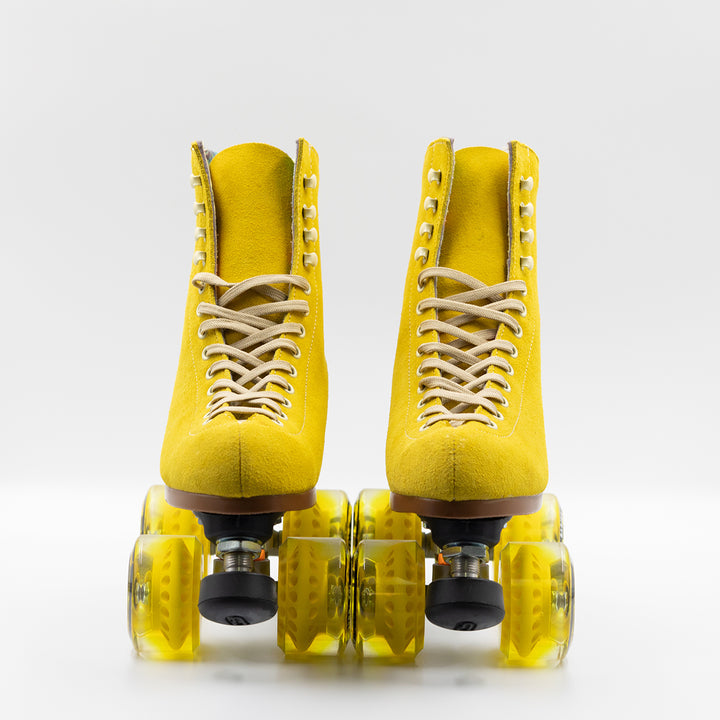 Moxi Roller Skates Lolly roller skates in Pineapple yellow with oyster laces and eyelets, tan sole, black plate and toe stop, matching yellow wheels.