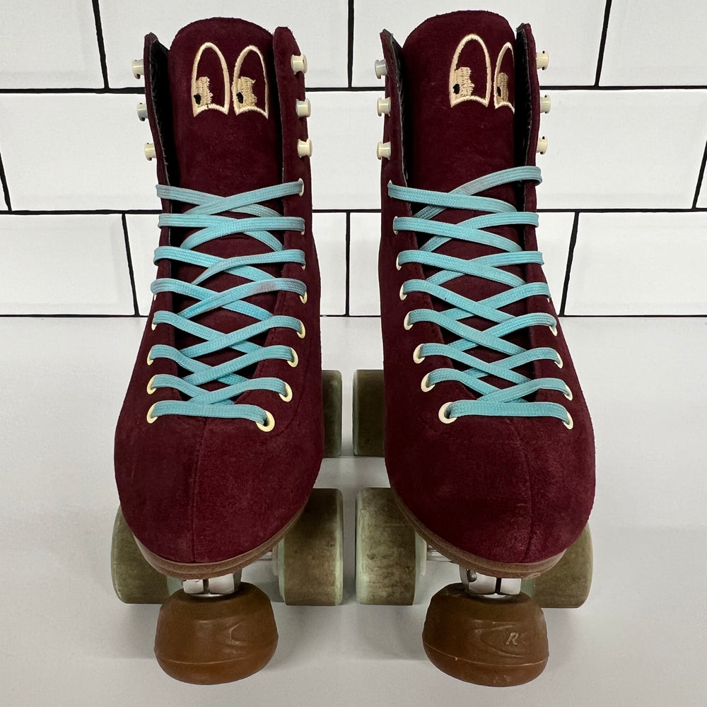 Pair of burgundy Chuffed custom setup roller skates with light blue laces on a white tiled background