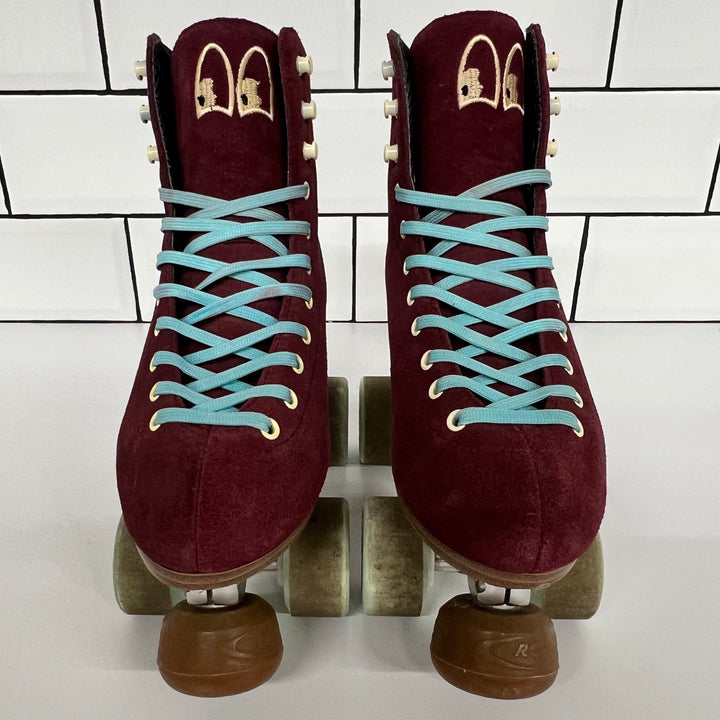 Pair of burgundy Chuffed custom setup roller skates with light blue laces on a white tiled background