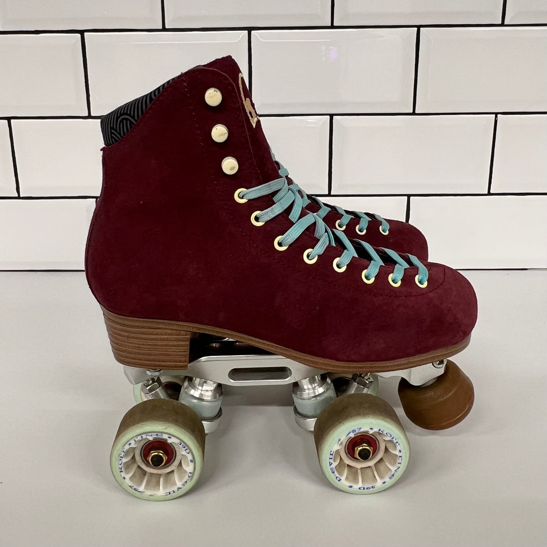 Pair of burgundy Chuffed custom setup roller skates with light blue laces on a white tiled background