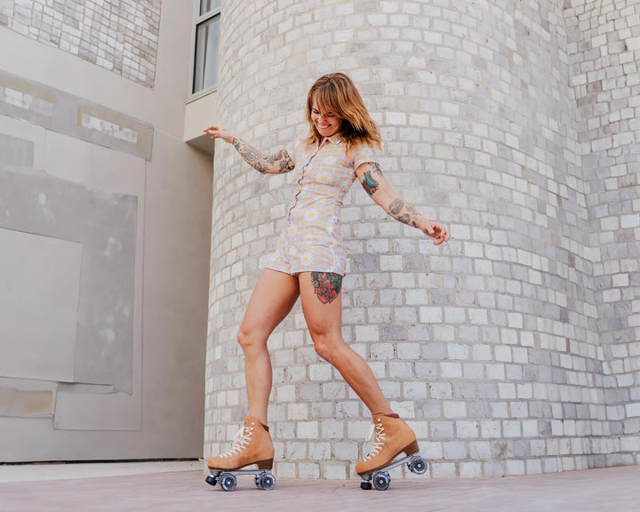 Sam wears a short light blue and orange retro onesie with the Caramel Wanderer roller skates.