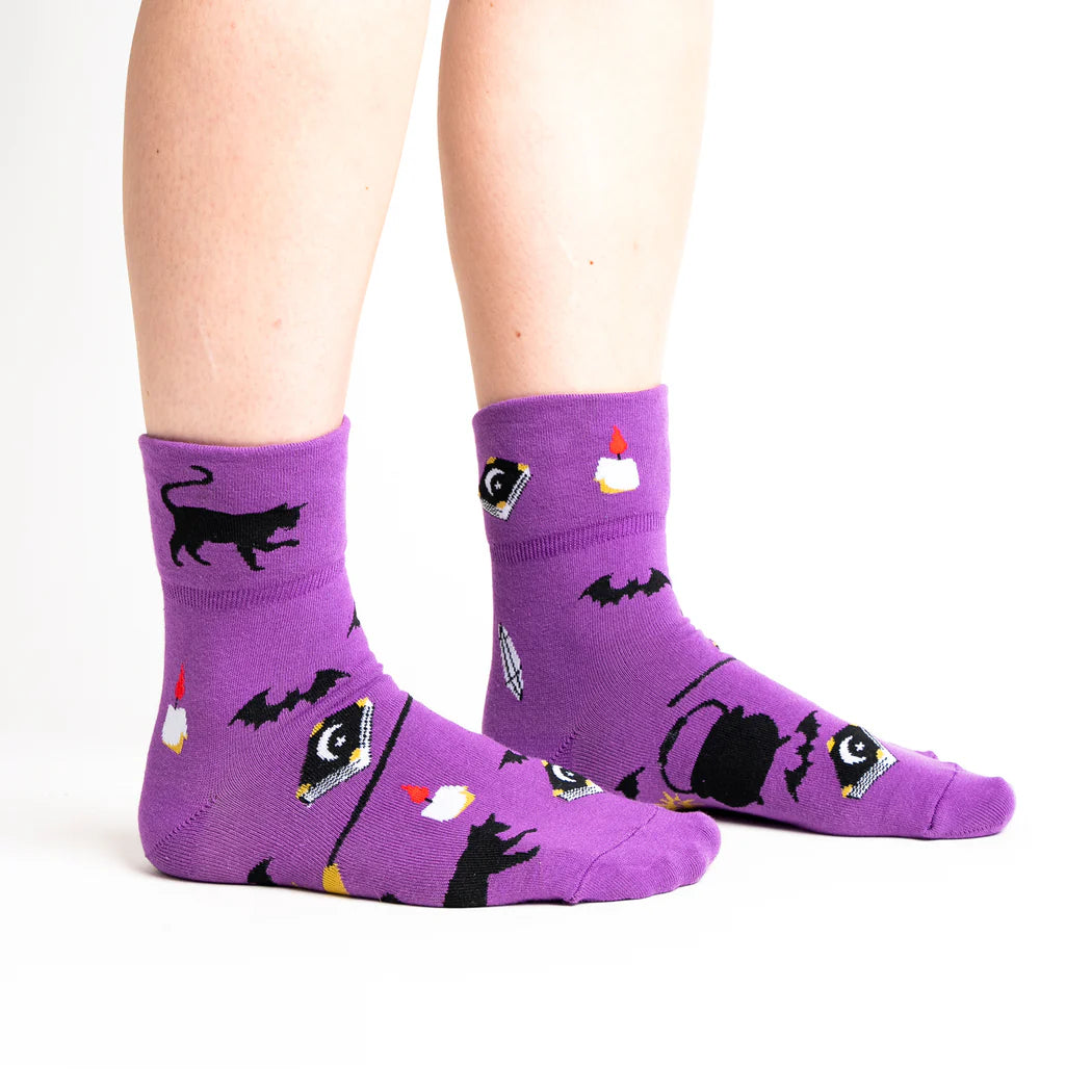 sock it to me turn cuff crew socks in grape purple with witches hats, cauldrons, cats, broomstick and spellbooks.