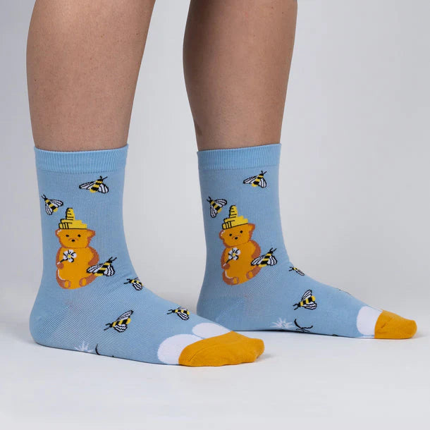 pastel blue socks with bees flying around a squeeze bottle of honey shaped like a bear.