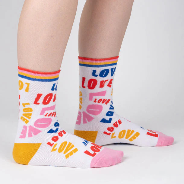 White crew sock with blue, red and pink stripe band at the top and large graphic repetitive text of "love" all over.