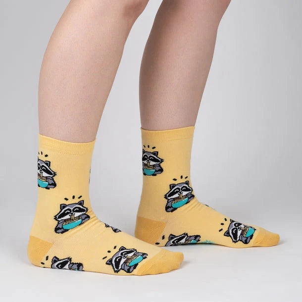 Pale yellow socks with cartoon raccoons slurplng up some ramen.