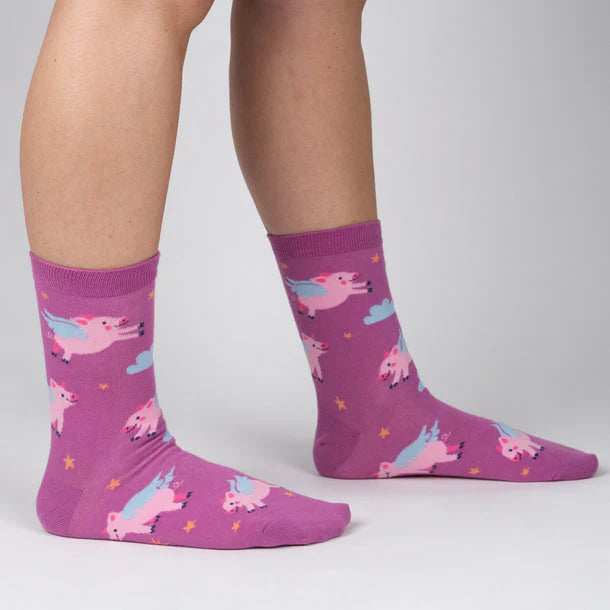 Magenta crew socks with cartoon pigs flying amongst yellow stars and grey clouds.