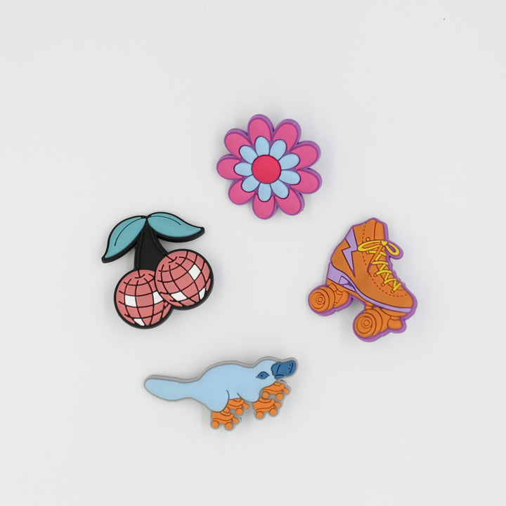 Croc charms designed for roller skaters. Four designs include disco cherries, RollerFit flower, classic skate and roller skating platypus.