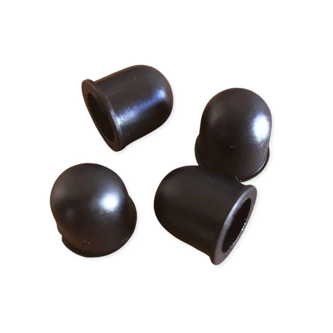 Four black rubber roller skate pivot cups on a white background