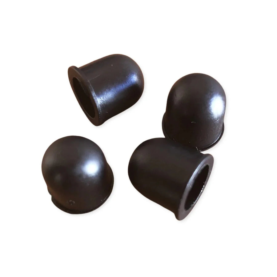 Four black rubber roller skate pivot cups on a white background