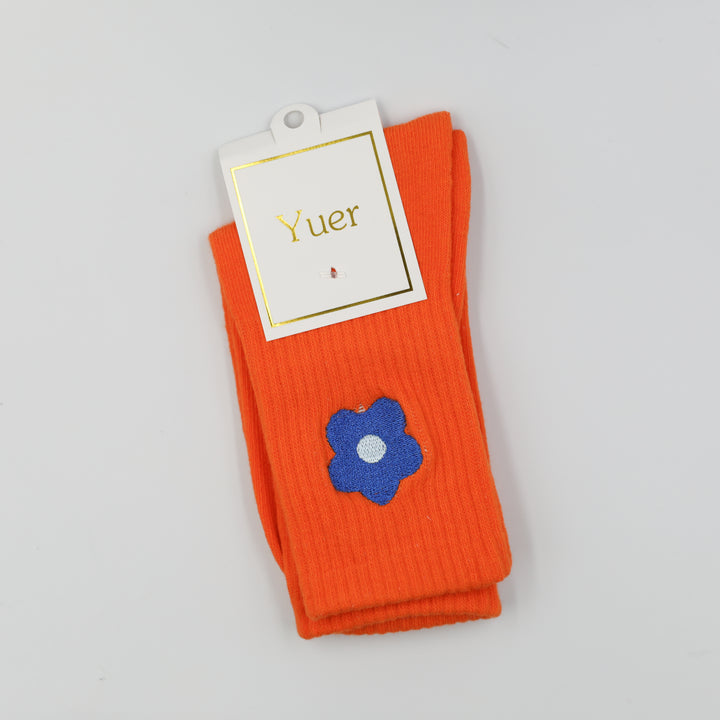 Bright orange ribbed crew socks with blue embroidered flower on the side above the ankle