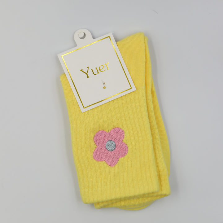 Pastel yellow ribbed crew socks with pink embroidered flower on the side above the ankle
