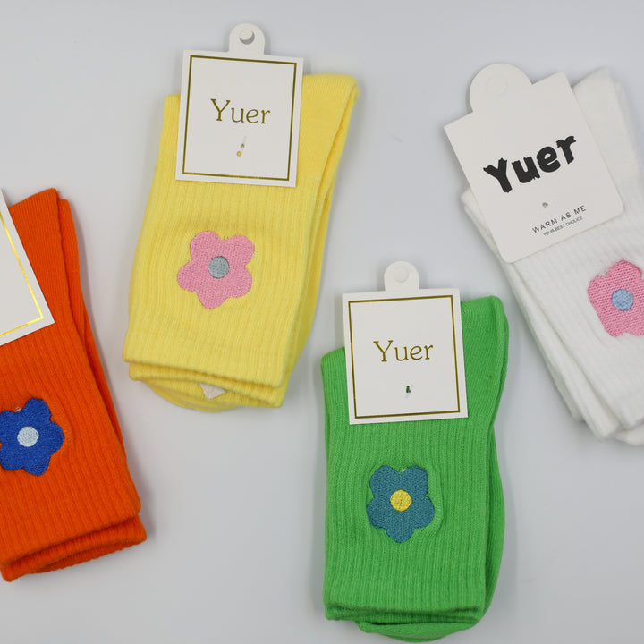 Colorful socks with embroidered flower designs on a white background
