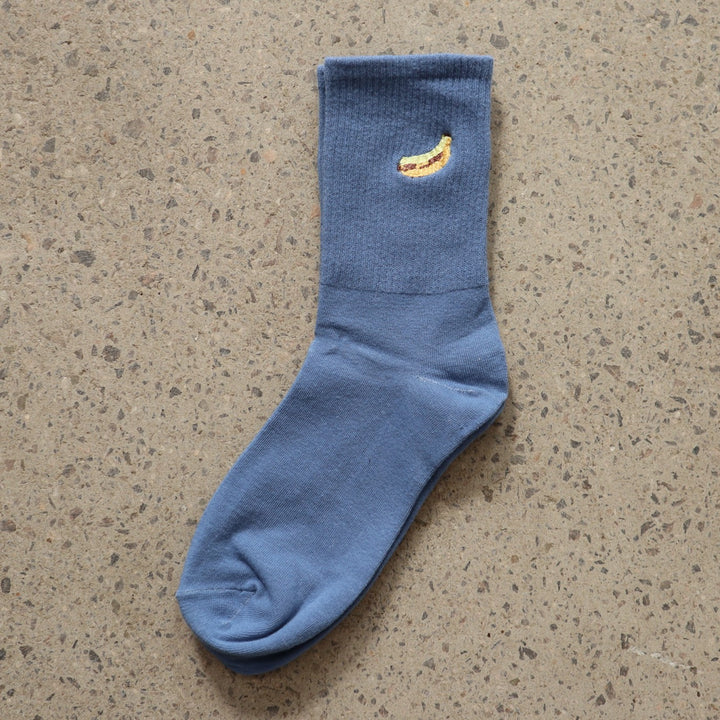 Blue RollerFit sock with yellow banana embroidered design on a gray surface