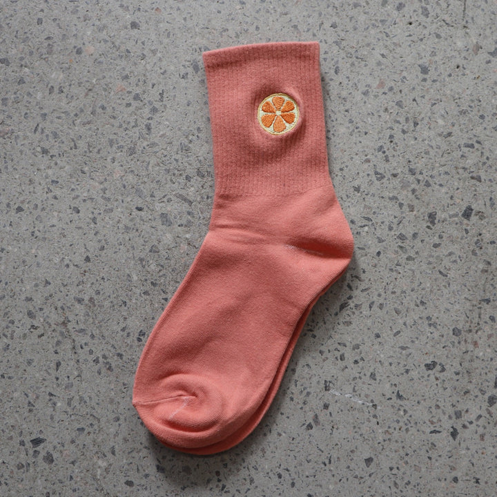 Orange RollerFit sock with orange slice embroidered design on a gray surface