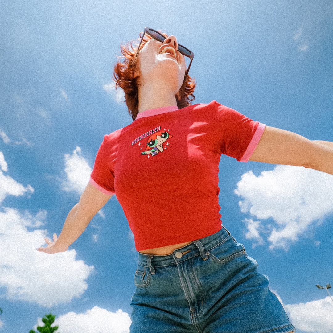 Peachy wears her signature burgundy and pink baby tee against a blue sky
