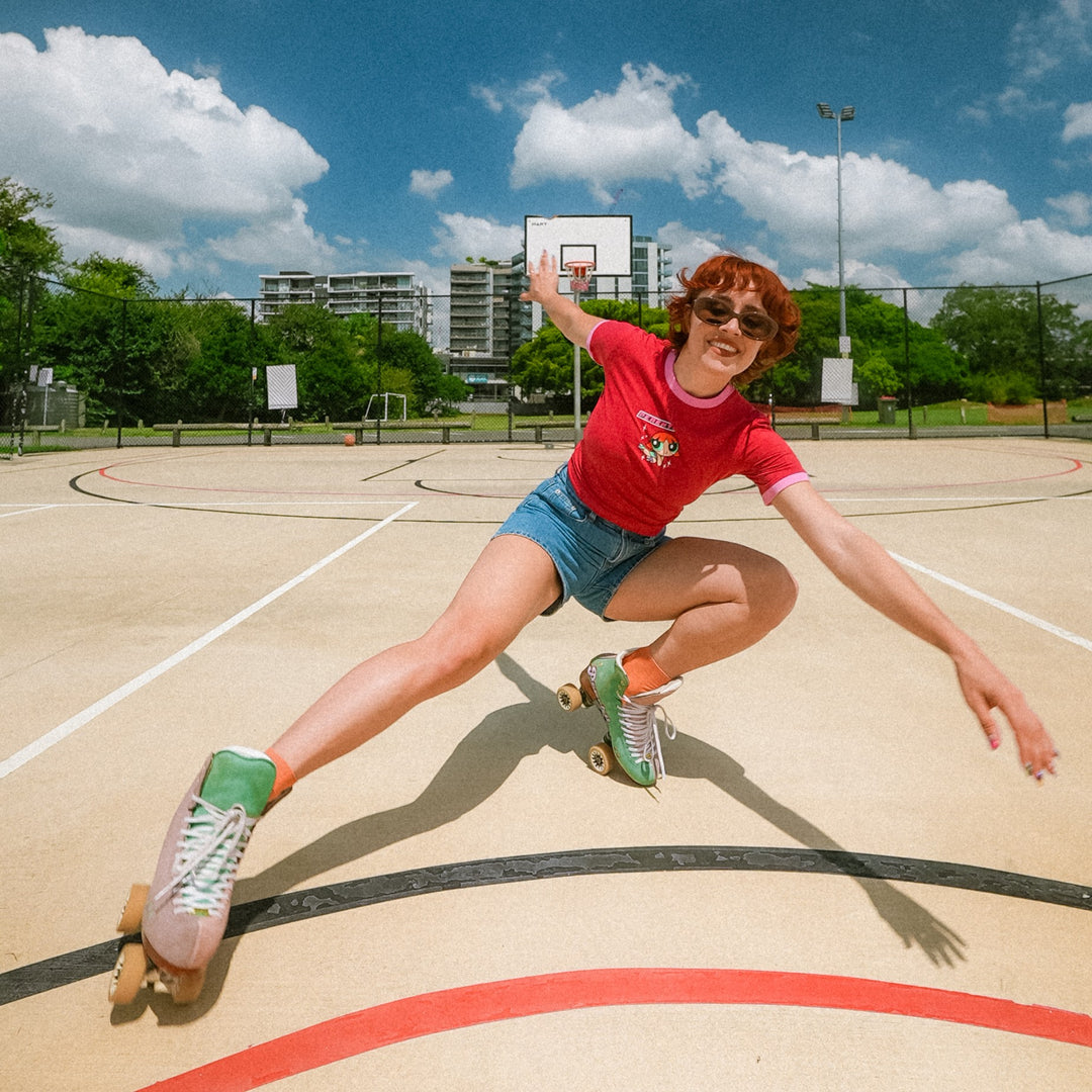Peachy roller skating on an outdoor basketball court with a blue sky and clouds in the background.