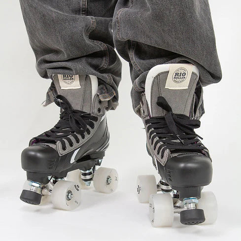 A person in black jeans wearing Rio Roller Flow Hockey skates with black and grey design on a white background