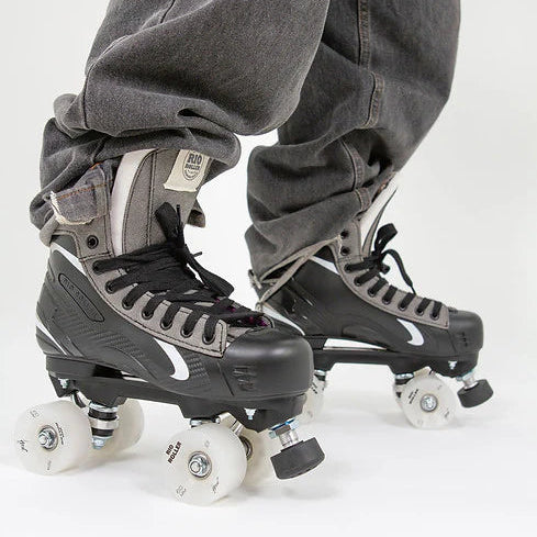 A person in black jeans wearing Rio Roller Flow Hockey skates with black and grey design on a white background