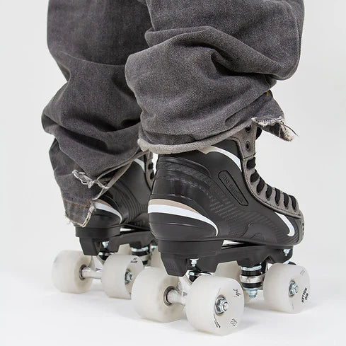 A person in black jeans wearing Rio Roller Flow Hockey skates with black and grey design on a white background