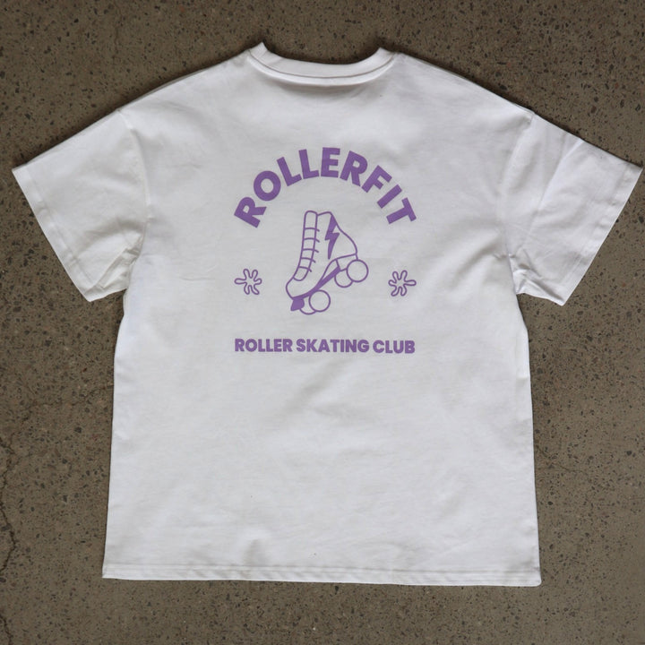 White t-shirt with purple 'Rollerfit Roller Skating Club' design on a brown surface