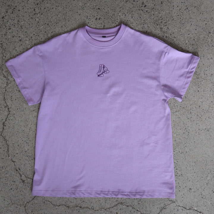 Purple t-shirt with a small roller skate logo on a concrete floor