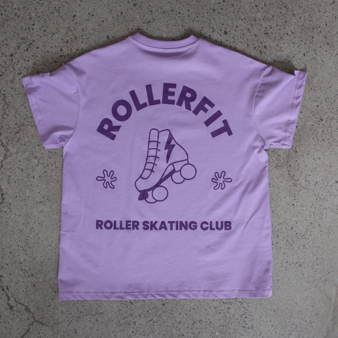 Purple t-shirt with 'ROLLERFIT Roller Skating Club' text and roller skate graphic on a concrete surface