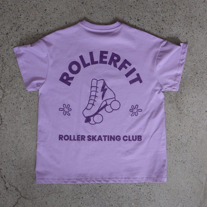 Purple t-shirt with 'ROLLERFIT Roller Skating Club' text and roller skate graphic on a concrete surface