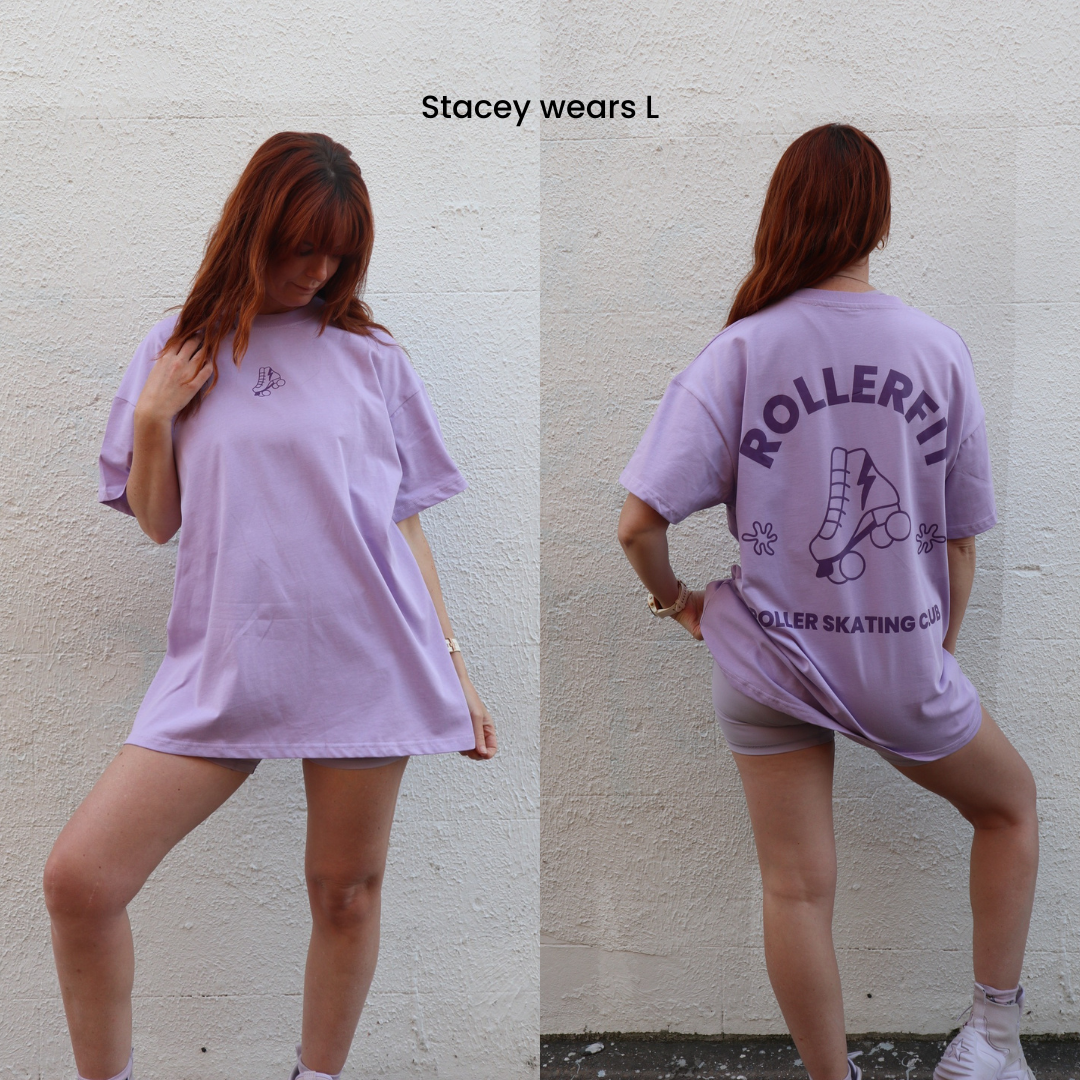Woman wearing a lilac oversized t-shirt with RollerFit roller skating club branding, standing against a plain wall.
