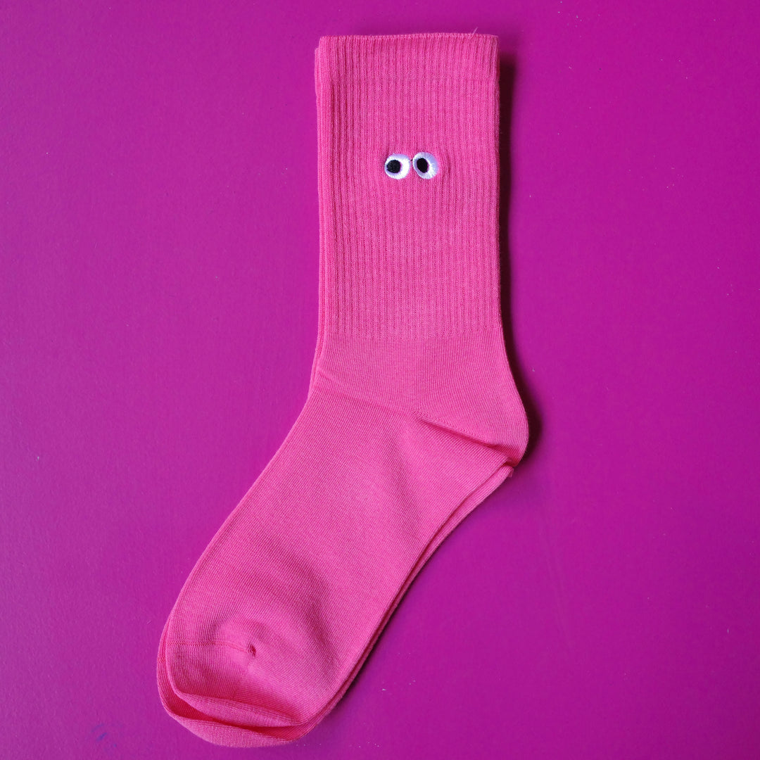 Bright pink coloured crew sock with embroidered cartoon eyeball design