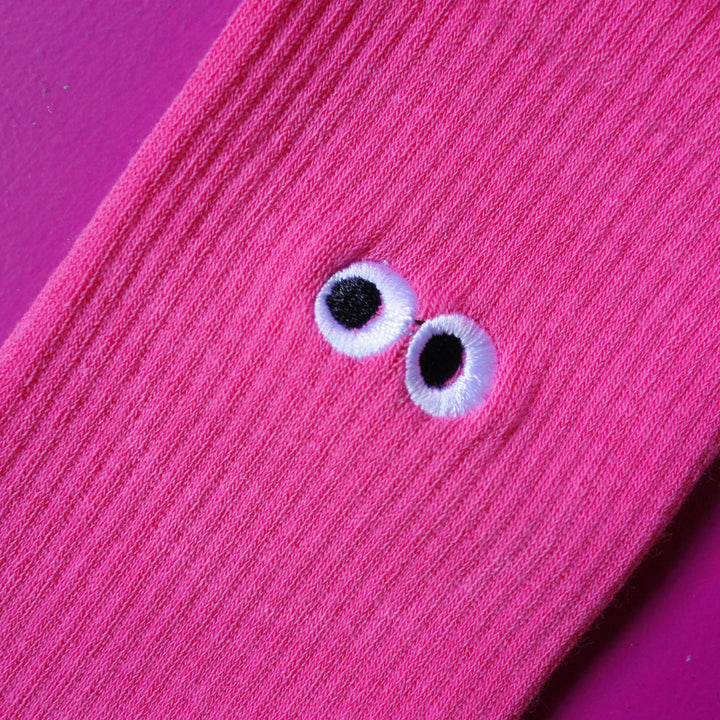 Close up of bright pink coloured crew sock with embroidered cartoon eyeball design