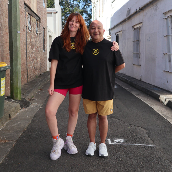 Stacey and Tony wearing the RollerFit x T-Roll anniversary black and yellow oversized t-shirt