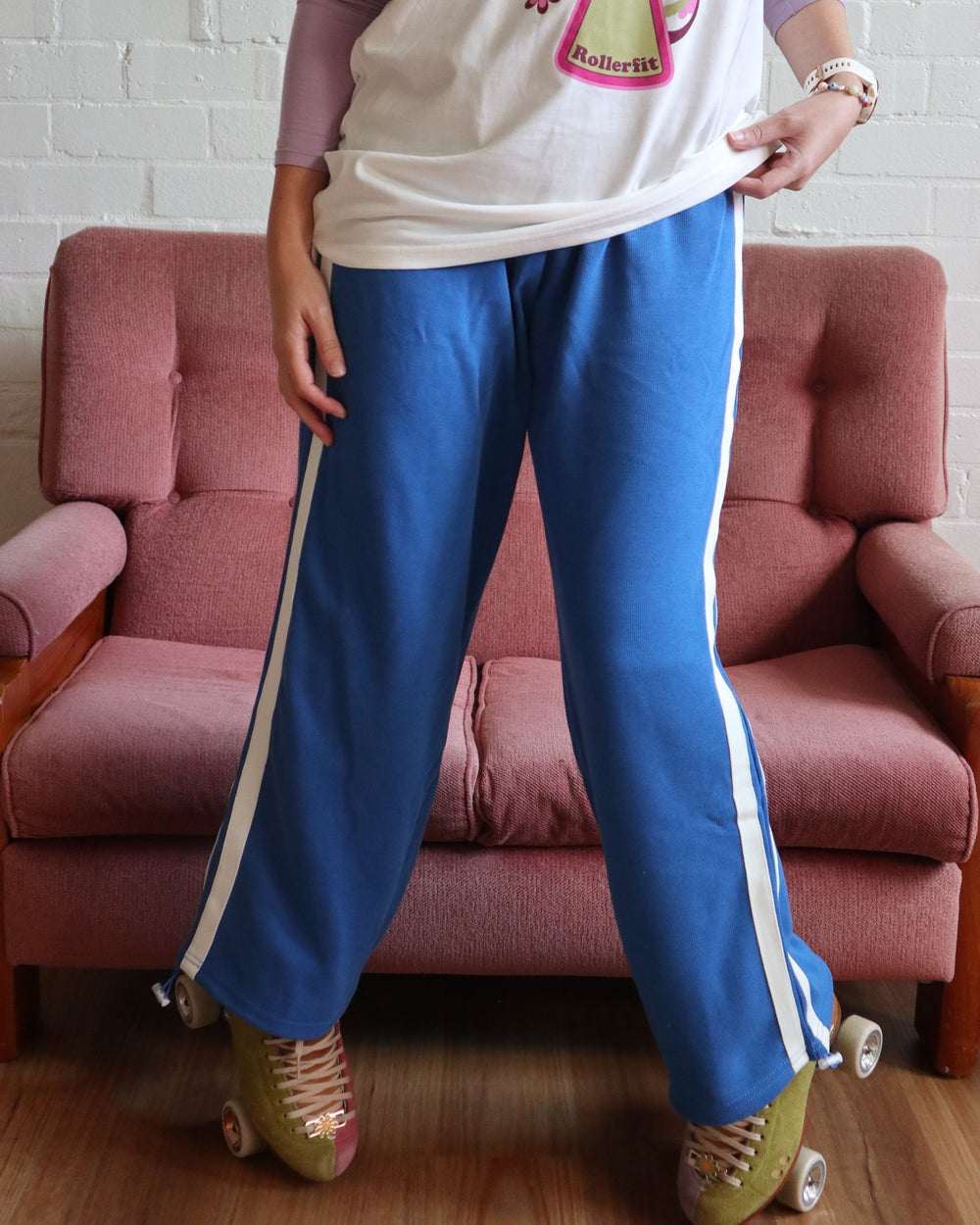 Stacey wears the blue wide leg stripe track pants from the RollerFit Shop with her roller skates