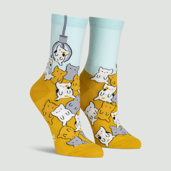 Mustard and baby blue socks with grey, white and mustard cartoon cats being picked up by machine claw.