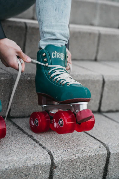 Skater lacing up Chaya roller skates with red Neons wheels.