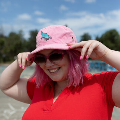 Emily wears the RollerFit pink corduroy bucket hat with blue skating platypus design.