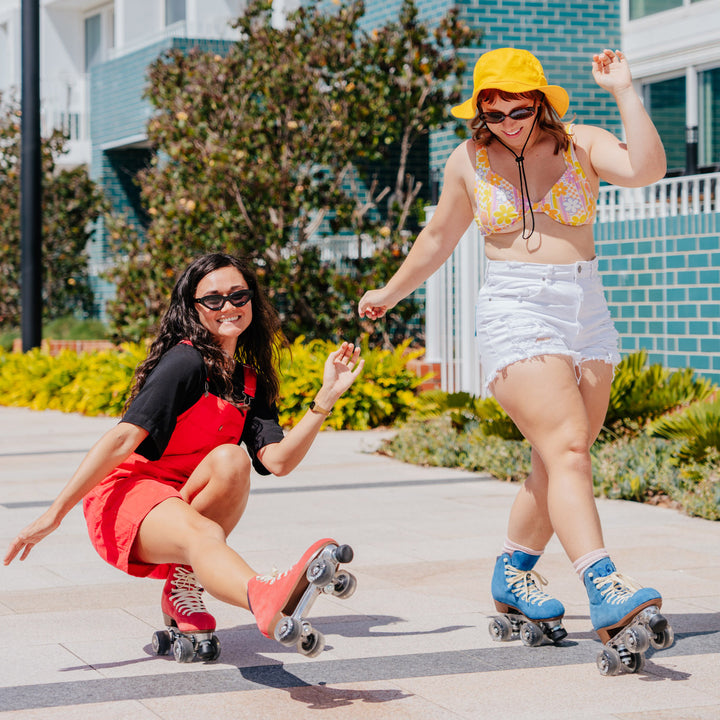 Mel does a Shoot the Duck wearing Chuffed Skates Watermelon Red Wanderer and Kirralee skates next to her upright wearing the Classic Blue Wanderer. 