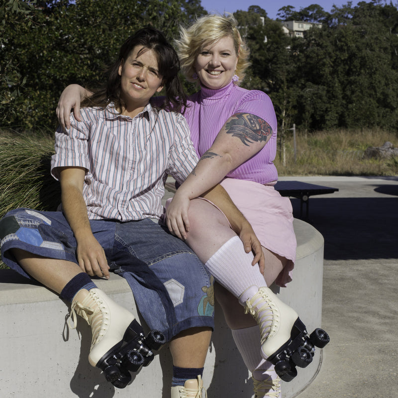 Emily and Bowzer are sitting with arms around each other wearing Sunset and Sunrise Cruiser roller skates respectively.