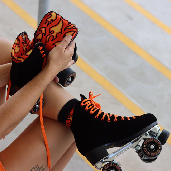 Chuffed Skates Fuegote roller skates with black suede boots, toe stops, wheels and orange laces, eyelets, logo embroidery and a piping hot flame lining.
