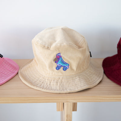 RollerFit Sand Galah bucket hat, sandy cream colour with blue roller skate and pink galah embroidered design.