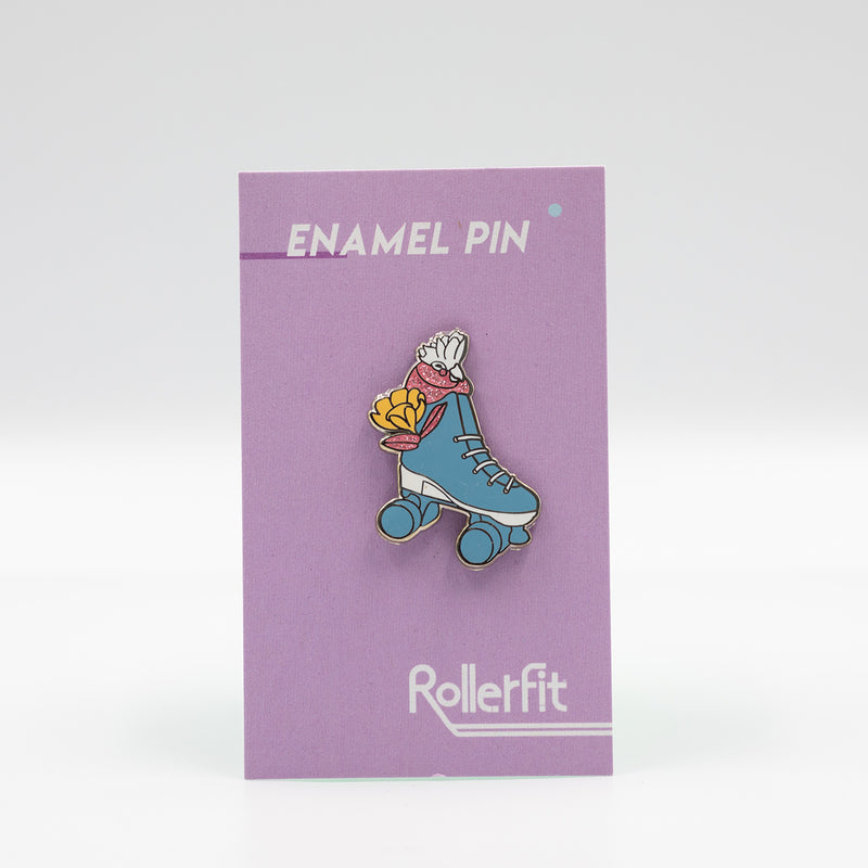 RollerFit Galah enamel pin with blue and white roller skate, pastel yellow flower and sparkly pink galah head.