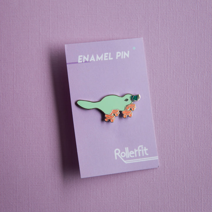 RollerFit enamel pin platypus in aqua with orange glitter skates and glitter dark teal beak.