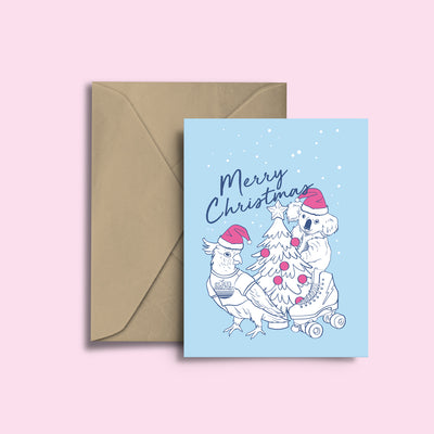 RollerFit Merry Christmas card with baby blue background, navy text and white and fuschia design with cockatoo, koala, christmas tree and a roller skate.