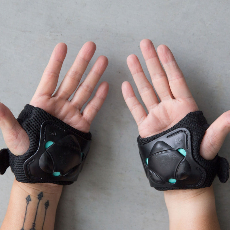 Rachel wears the RollerFit Palm Slider a light weight protective guard for your hands in black with blue accents.