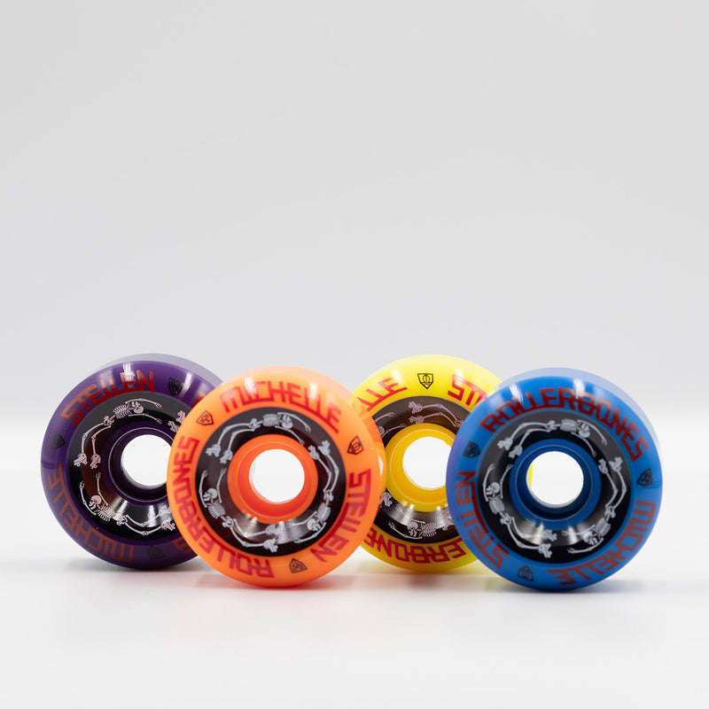 Rollerbones x Michelle Steilen Bowl Bomber wheels 4 pack with 1 purple, 1 orange, 1 yellow and 1 blue wheel with black, white and red print.