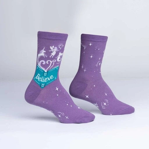 Purple socks with teal book saying "believe" with whisping magical creatures floating out.